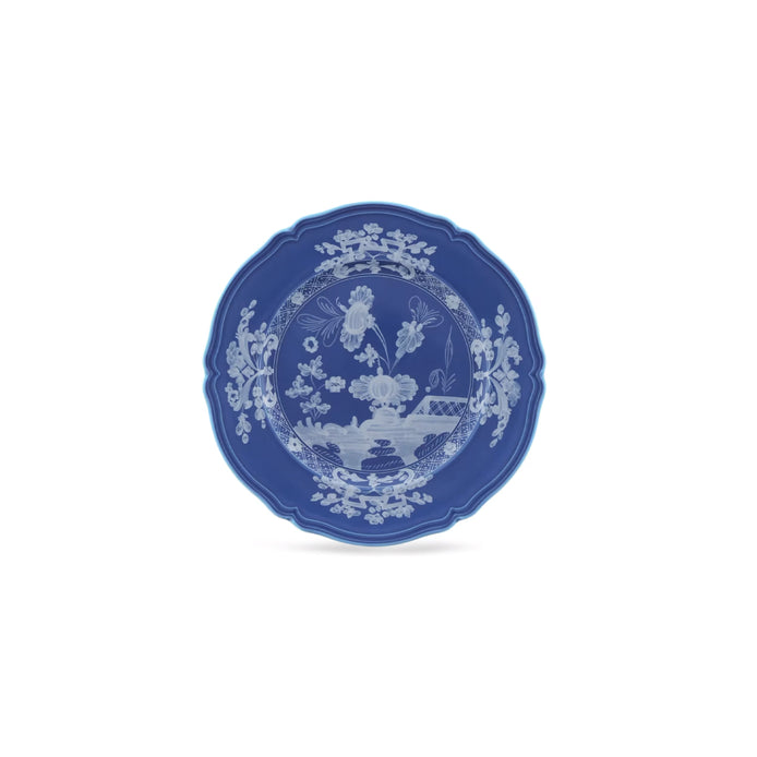 A blue ceramic plate with a white hand-painted chinoiserie floral and landscape design, centered on a plain white background.