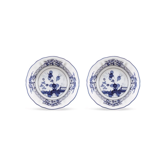 Two round white ceramic plates with blue floral and landscape illustrations, arranged side by side on a white background.