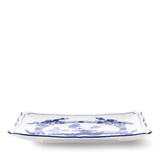 A rectangular white ceramic serving platter with scalloped edges and a blue floral pattern, shown on a clean white background.