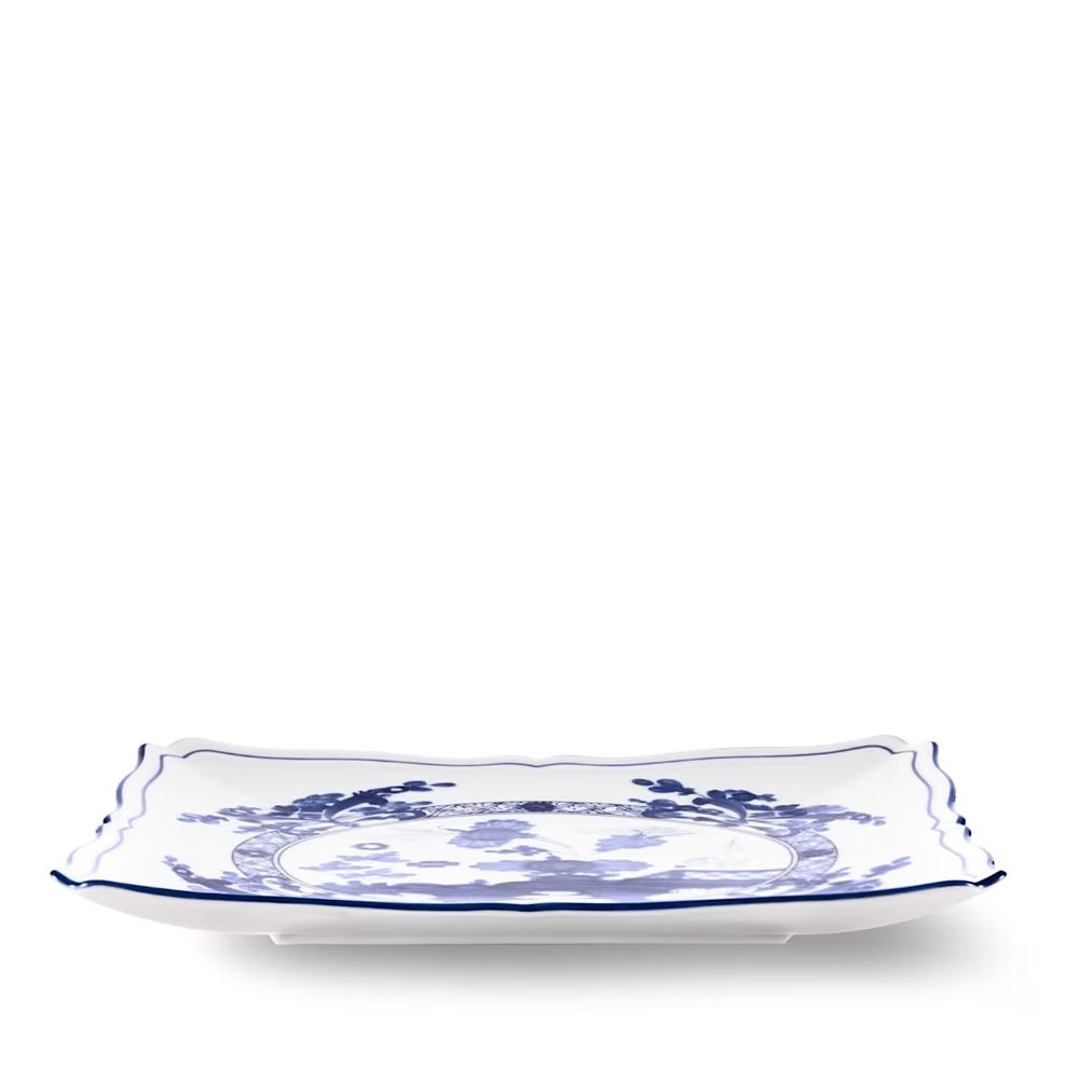A rectangular white ceramic serving platter with scalloped edges and a blue floral pattern, shown on a clean white background.