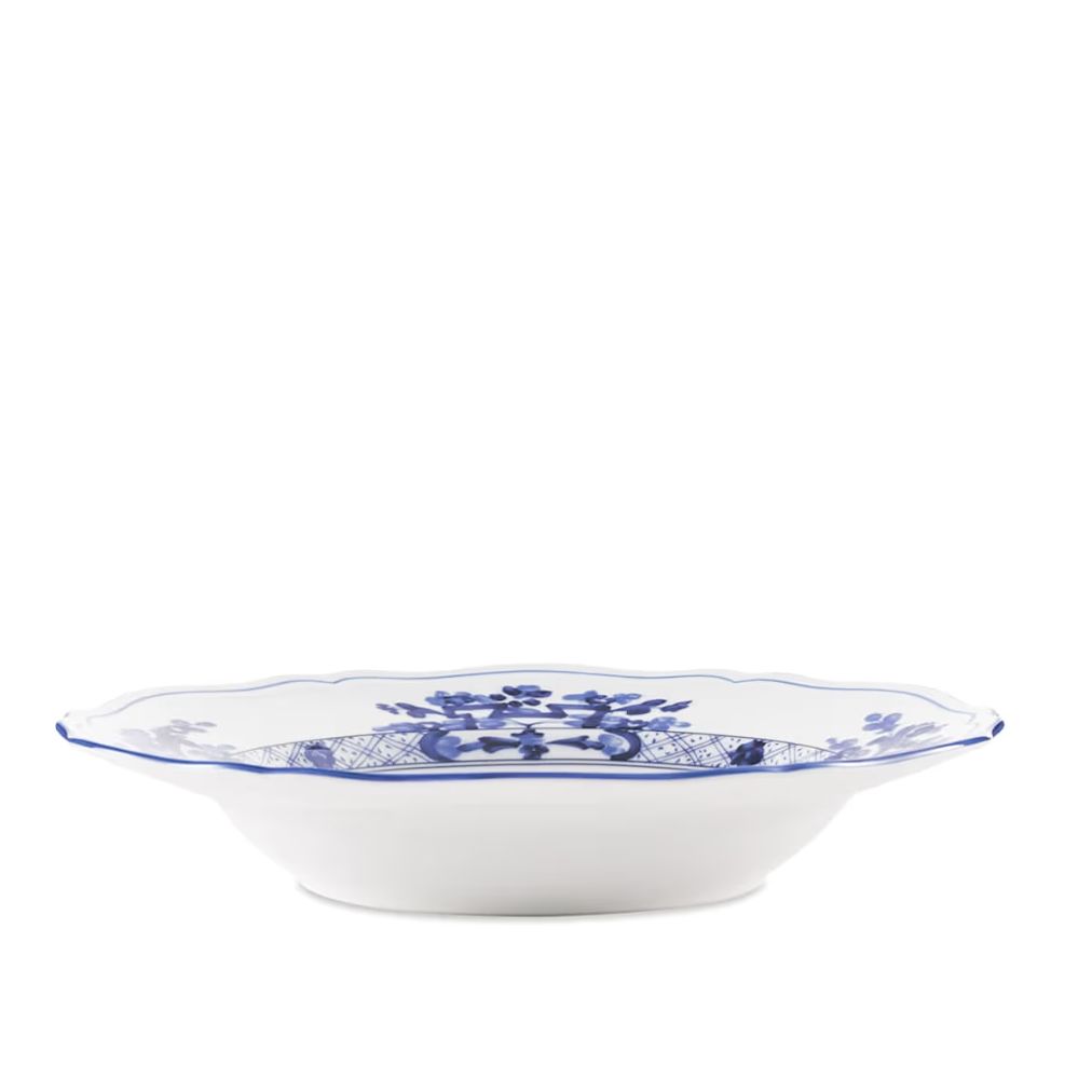 A white ceramic bowl with a scalloped rim, decorated with a blue floral and crest pattern, shown against a plain white background.