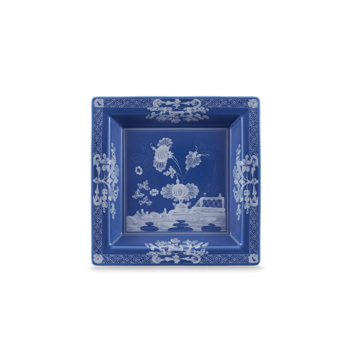 A square blue ceramic plate with white floral and landscape illustrations, shown from a top-down view on a white background.