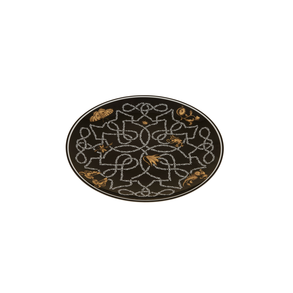 An oval black rug featuring an intricate white geometric pattern and scattered gold floral accents, shown against a plain white background.