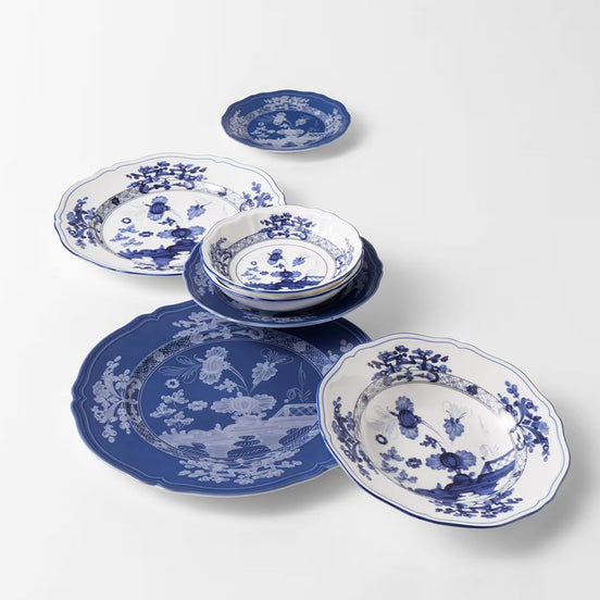 A set of blue and white ceramic tableware, including plates, bowls, and a small dish, arranged on a clean white background.