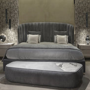 The Empire Bed by Medea 1905 embodies the essence of contemporary Italian living through refined craftsmanship, enveloping volumes, and luxurious materiality. Its signature wingback headboard, defined by elegant vertical channel stitching, rises in a graceful curve that gently wraps the sleeping area, creating a sense of intimacy