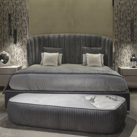 The Empire Bed by Medea 1905 embodies the essence of contemporary Italian living through refined craftsmanship, enveloping volumes, and luxurious materiality. Its signature wingback headboard, defined by elegant vertical channel stitching, rises in a graceful curve that gently wraps the sleeping area, creating a sense of intimacy