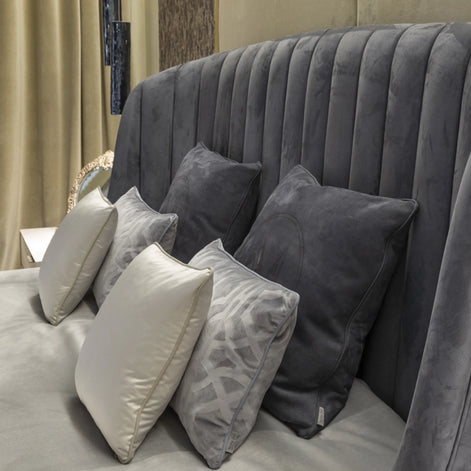 The Empire Bed by Medea 1905 embodies the essence of contemporary Italian living through refined craftsmanship, enveloping volumes, and luxurious materiality. Its signature wingback headboard, defined by elegant vertical channel stitching, rises in a graceful curve that gently wraps the sleeping area, creating a sense of intimacy