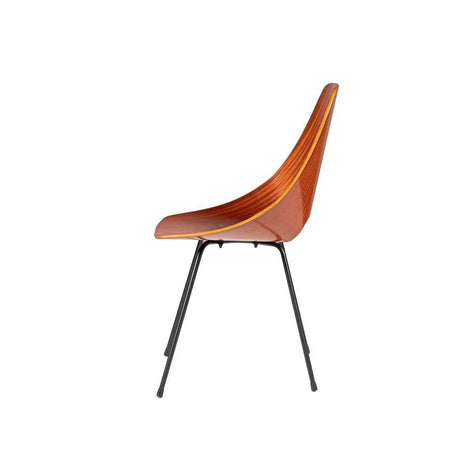 An icon of twentieth-century design, the Sedia Medea is defined by a single continuous shell in moulded plywood with a glossy mahogany veneer — a fluid, ergonomic curve pierced by the signature handle-like opening that lends the chair its unmistakable identity. The sculptural shell rests upon a slender matt-black painted iron structure, grounded by discreet black rubber pads, while four golden studs on the seat provide an exquisite detail of refined ornamentation. Noble materials including wood and metal ar