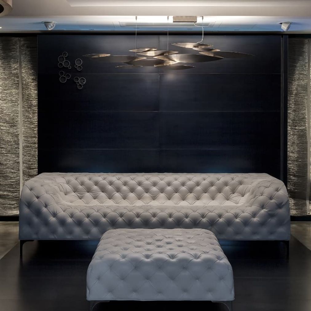 Terzani I Lucci Argentati linear chandelier in a bright living room above white seating, with overlapping sculptural elements and soft downward illumination.