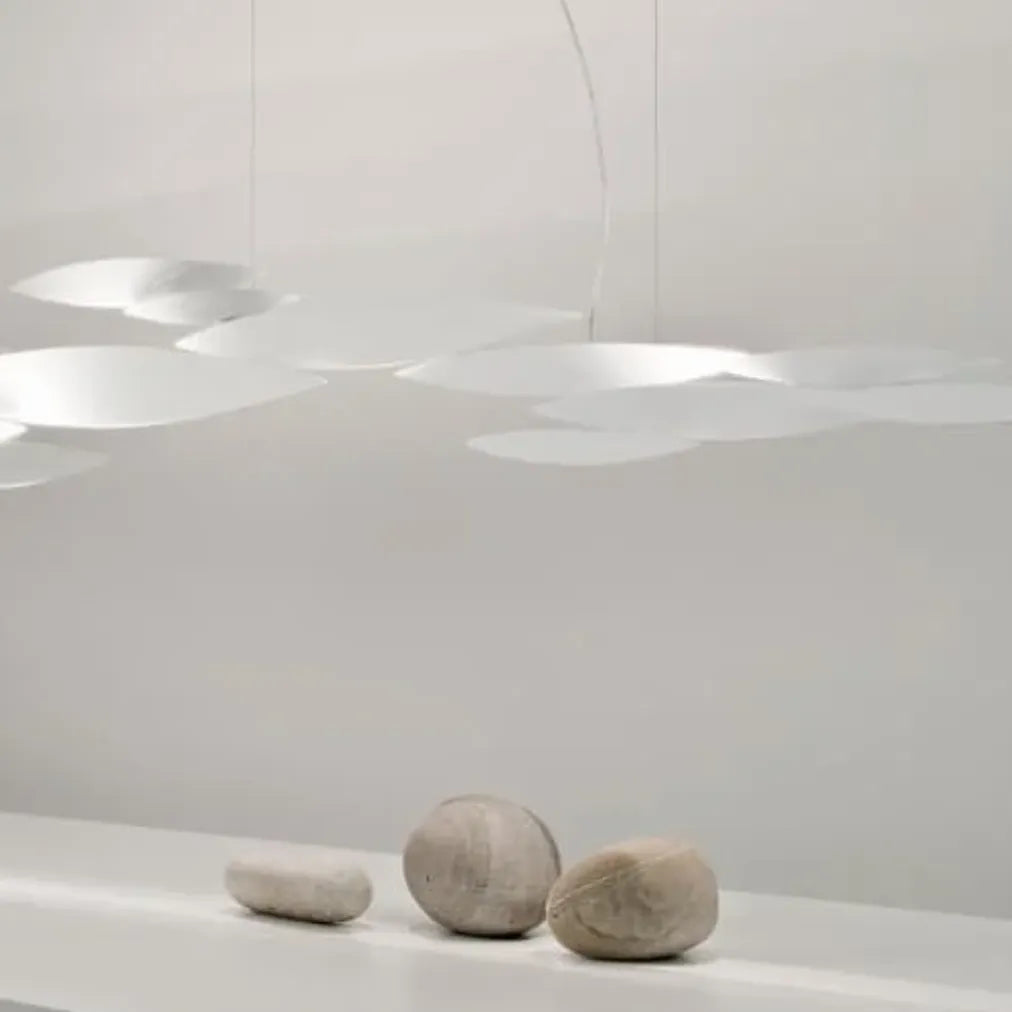 Gold-tone Terzani I Lucci Argentati linear chandelier above a white table in an ornate room, showing its flowing school-of-fish-inspired arrangement.