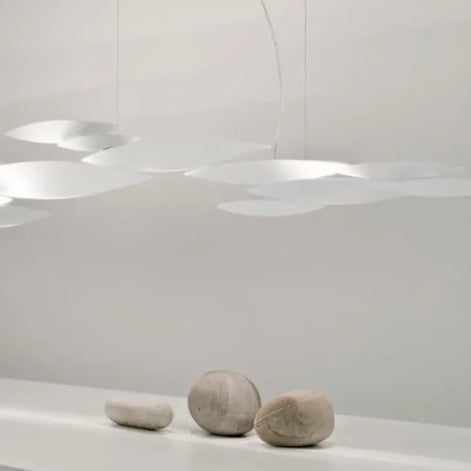 Gold-tone Terzani I Lucci Argentati linear chandelier above a white table in an ornate room, showing its flowing school-of-fish-inspired arrangement.