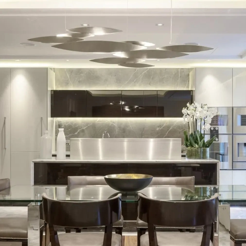 Silver-tone Terzani I Lucci Argentati chandelier suspended above a dark table, casting pools of downward light from its fish-inspired elements.