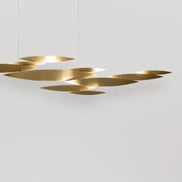 White Terzani I Lucci Argentati linear chandelier above a pale console with stone ornaments, showing its floating organic arrangement.