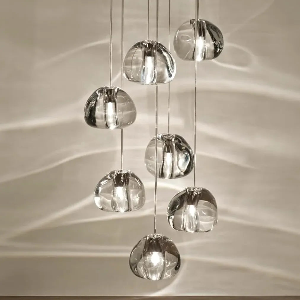 Close-up of an illuminated clear crystal shade on the Terzani Mizu 7 pendant light, showing its organic water-drop form and central light source.