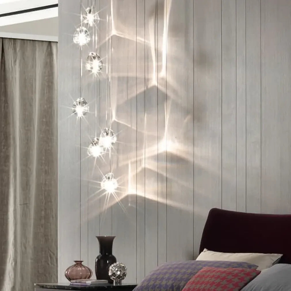 Terzani Mizu 7 pendant light suspended beside a dark curved staircase, with clear crystal shades casting wave-like reflections across the walls.