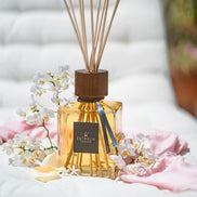 A reed diffuser bottle 'Rose Tuberose' by Euthalia Fragrances with a square glass body filled with amber liquid, a dark wood-toned reed cap, and natural reed sticks. At Archideco Interior Gallery.