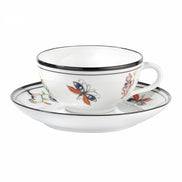 A white porcelain teacup and saucer set with delicate black rim detailing and colorful painted floral and butterfly motifs, shown on a plain white background.