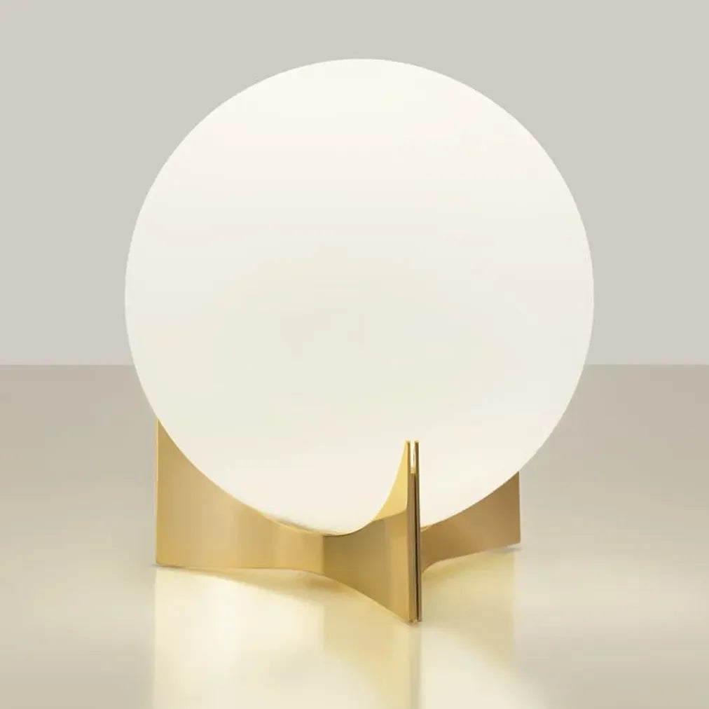 Terzani Oscar table lamp with an illuminated opal glass globe and sculptural gold-tone base, shown at an angle on a light background.