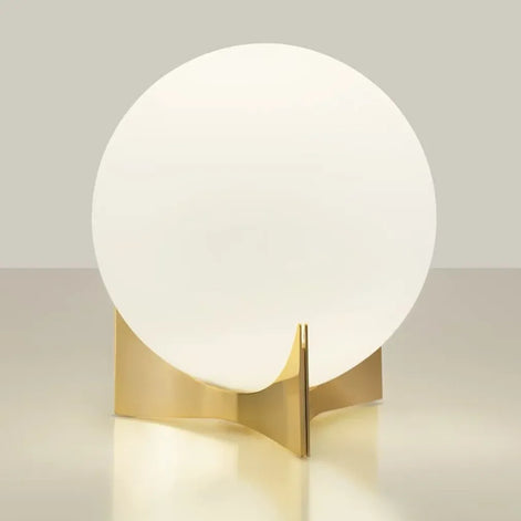Terzani Oscar table lamp with an illuminated opal glass globe and sculptural gold-tone base, shown at an angle on a light background.